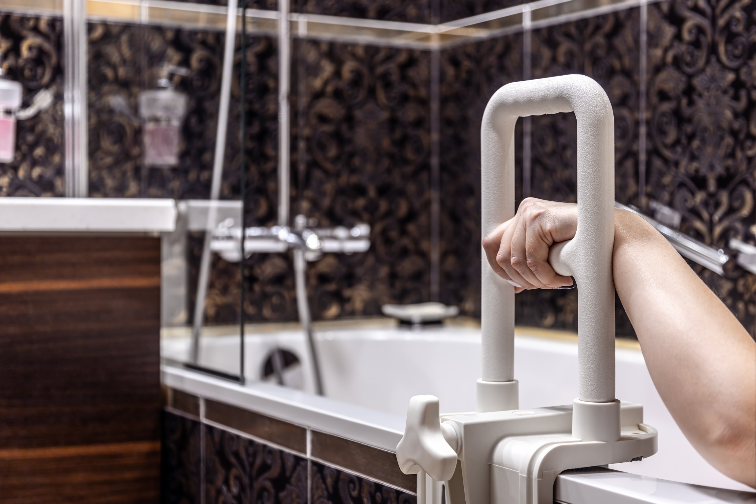 A woman in a bathtub holds a grab bar.